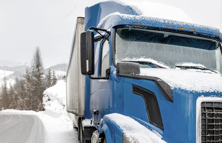 Diesel semi-truck pulled over on the side of a road in winter.