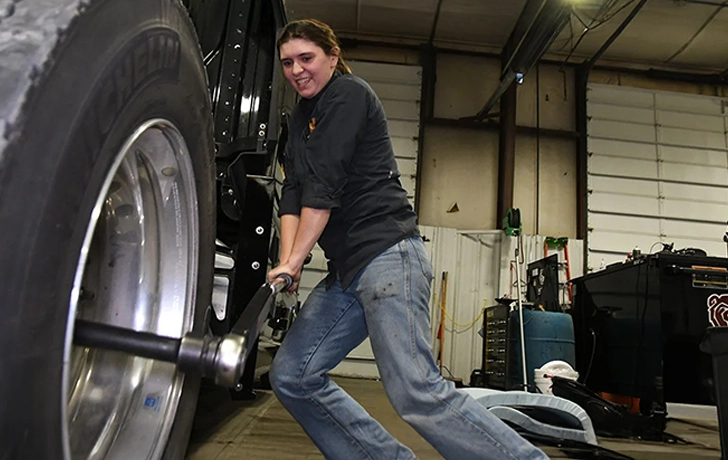 Female diesel mechanic working on the tire of a tractor trailer