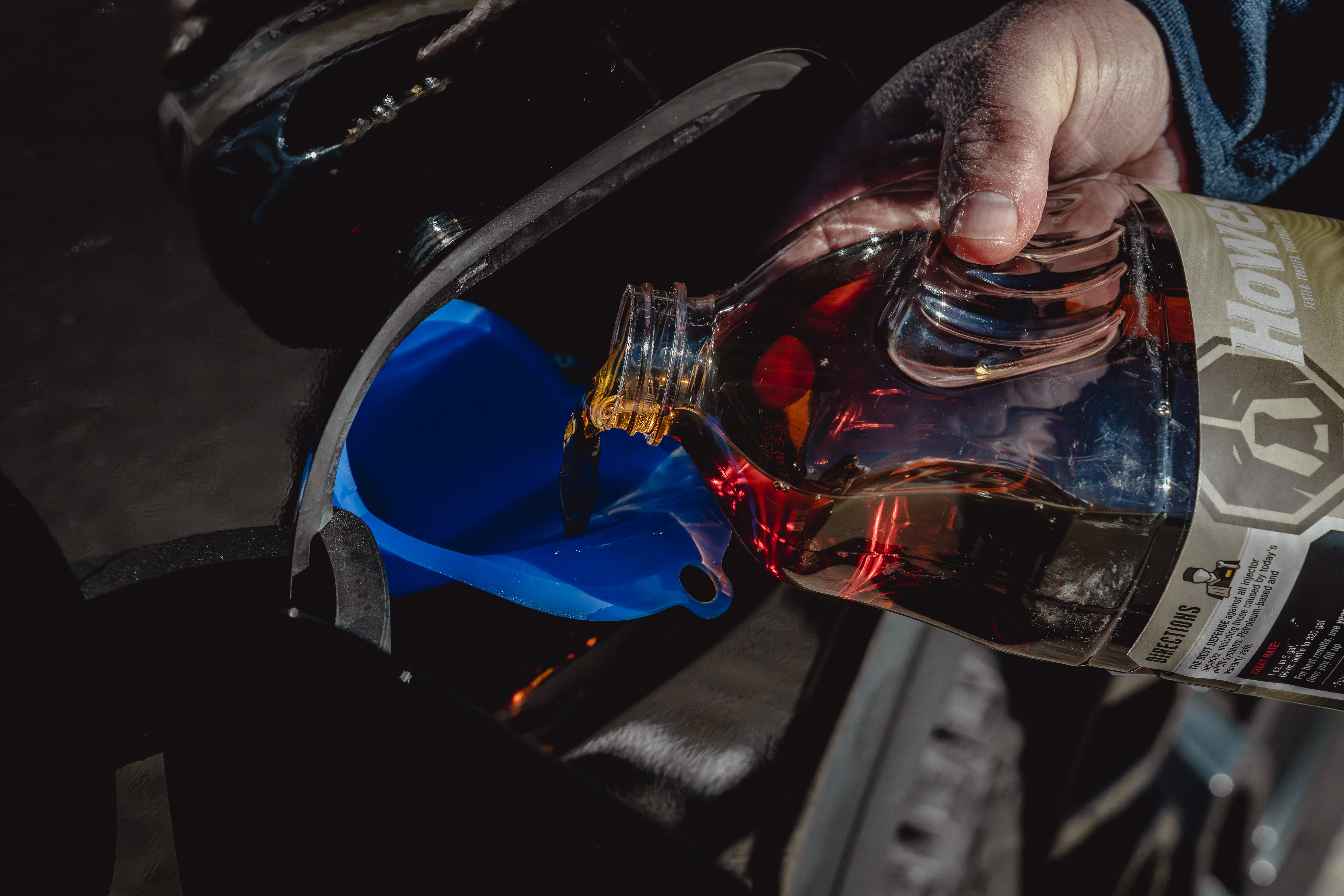 Hand pouring Howes Diesel Defender injector cleaner diesel additive into diesel pickup tank.