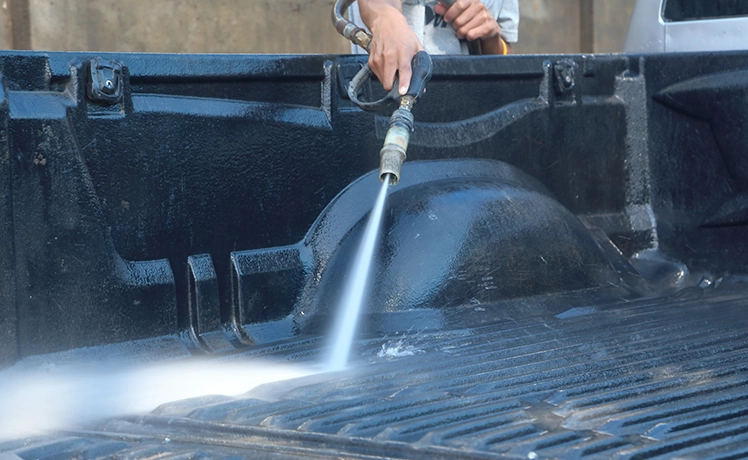Spraying a truck bed with a high-pressure washer