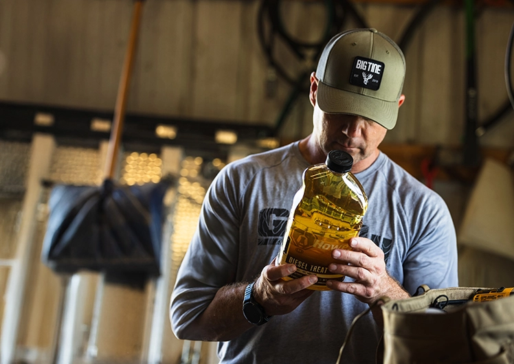 Man reading the instructions on a bottle of Howes Diesel Treat Anti-gel and Fuel Conditioner.